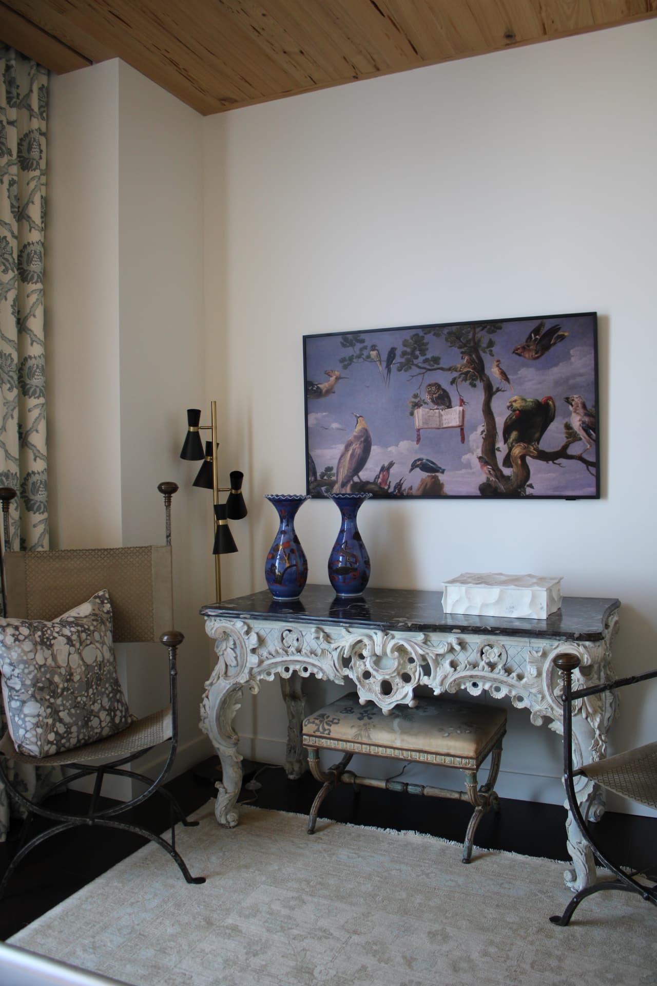 Carved painted console with a black marble top, blue chinoiserie vases, and a bird painting above — Downtown Nashville, Nashville