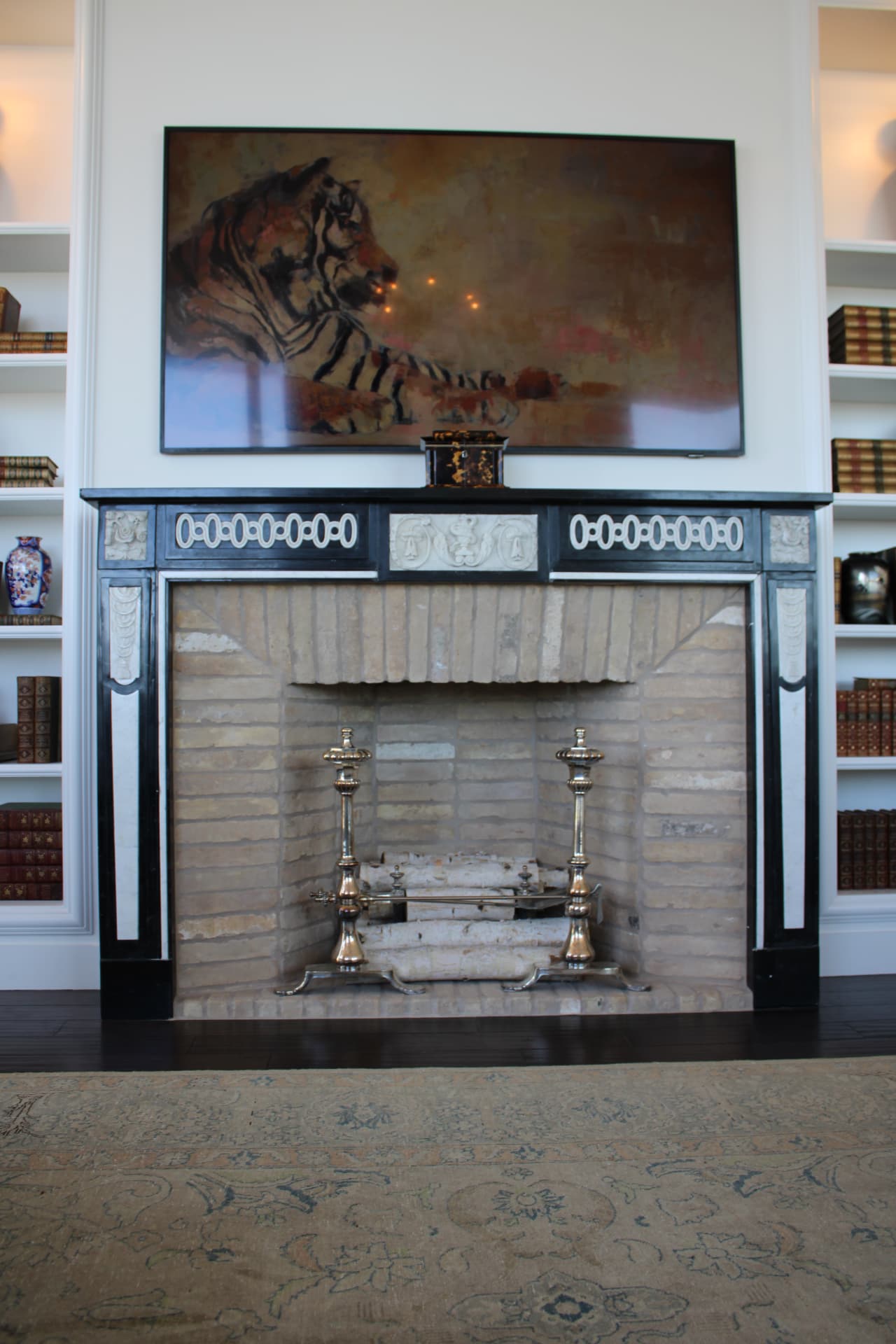 Library fireplace with a black-and-white carved mantel, brass andirons, and a tiger painting above — Downtown Nashville, Nashville
