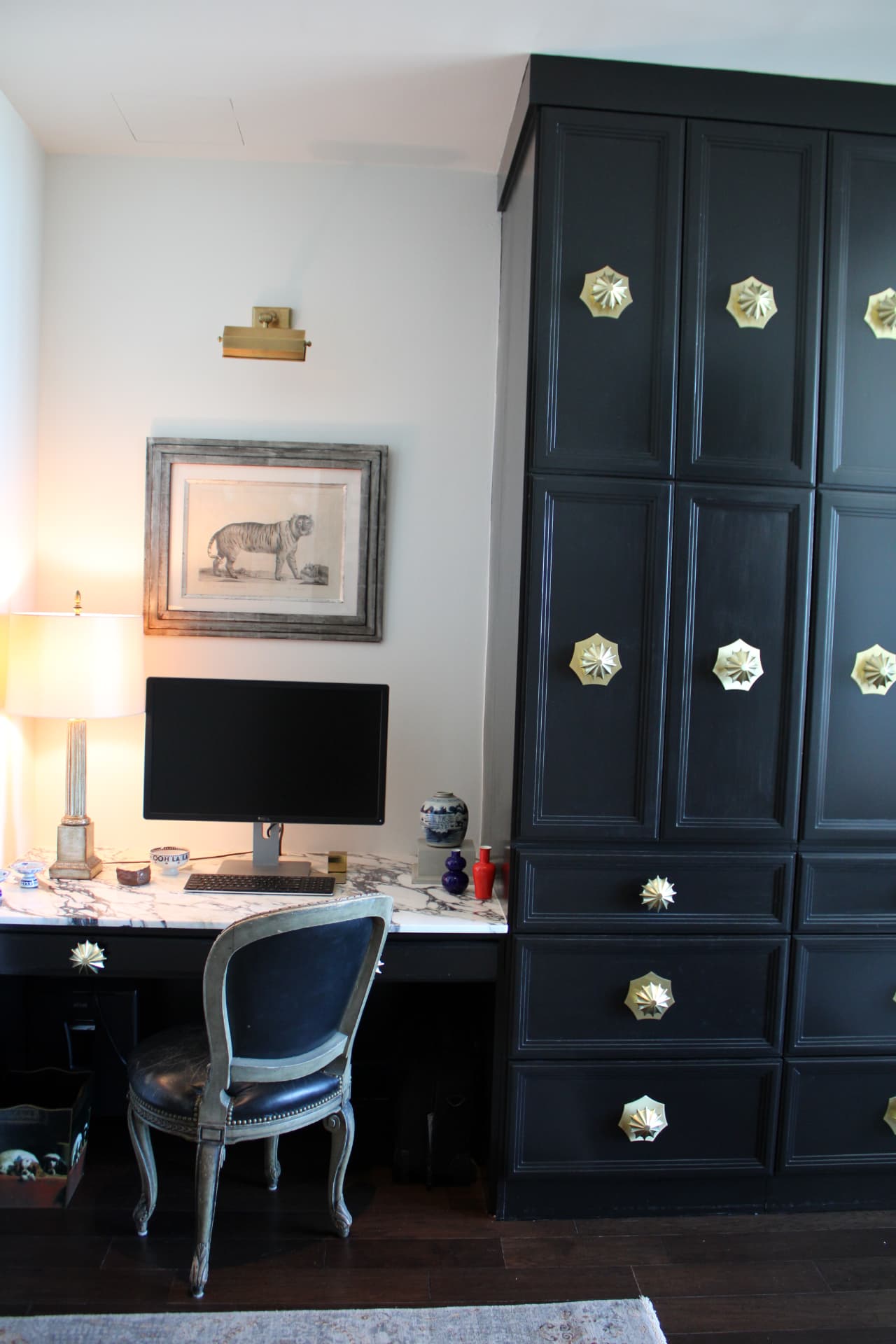 Black lacquered cabinets with starburst brass hardware beside a marble-topped desk and a French chair — Downtown Nashville, Nashville