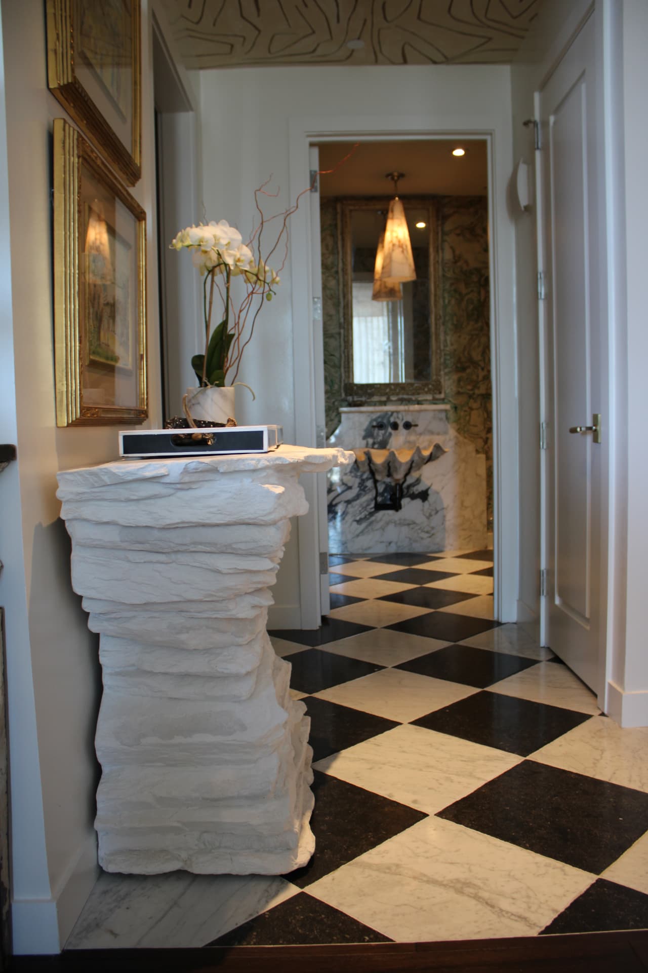 Plaster-stacked console with an orchid above a black-and-white checkered marble floor — Downtown Nashville, Nashville